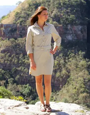 A lady wearing the Rufiji safari shirt dress on a rock in the bush